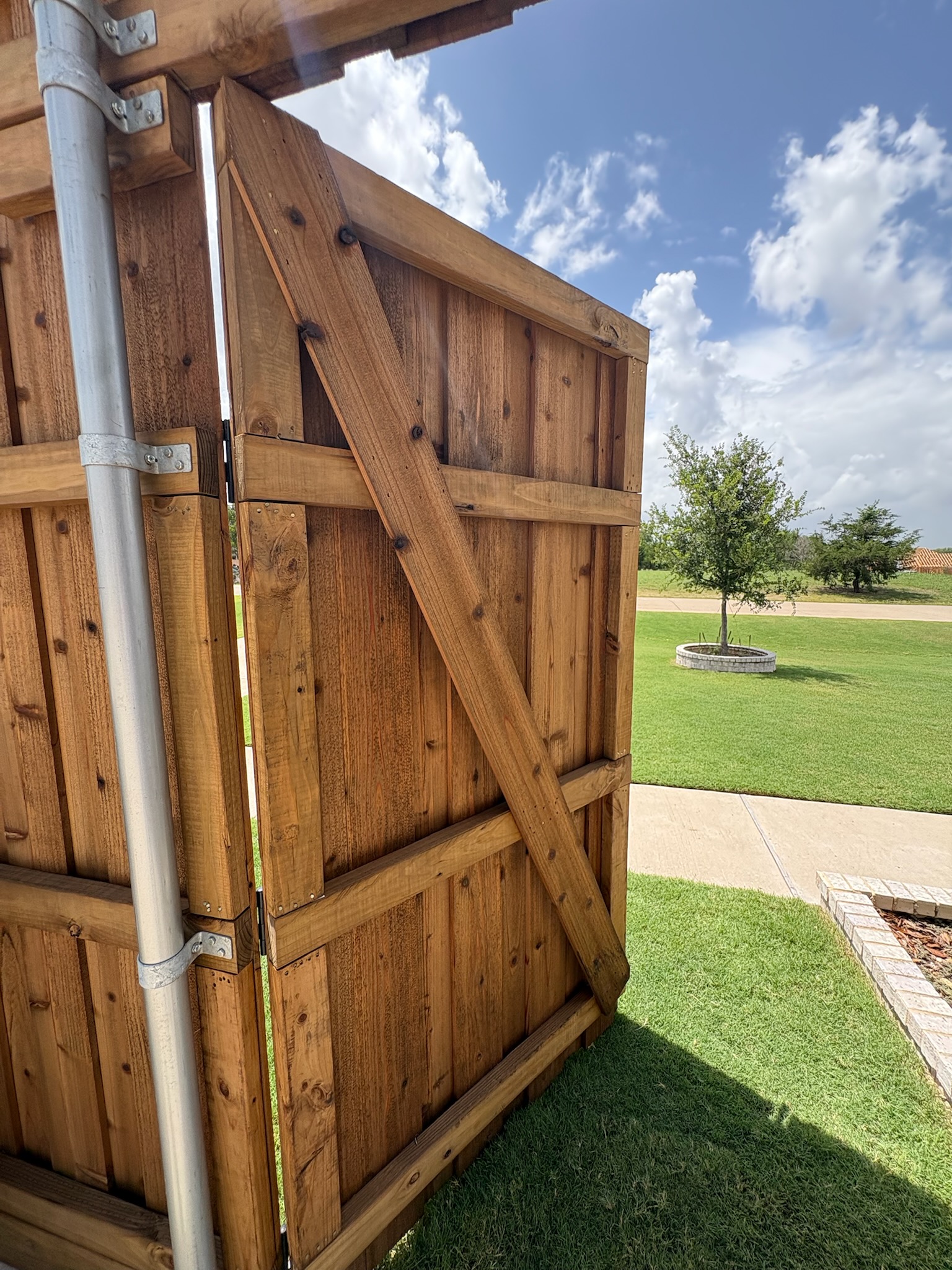 Cedar privacy fence with a braced gate leading to a front lawn