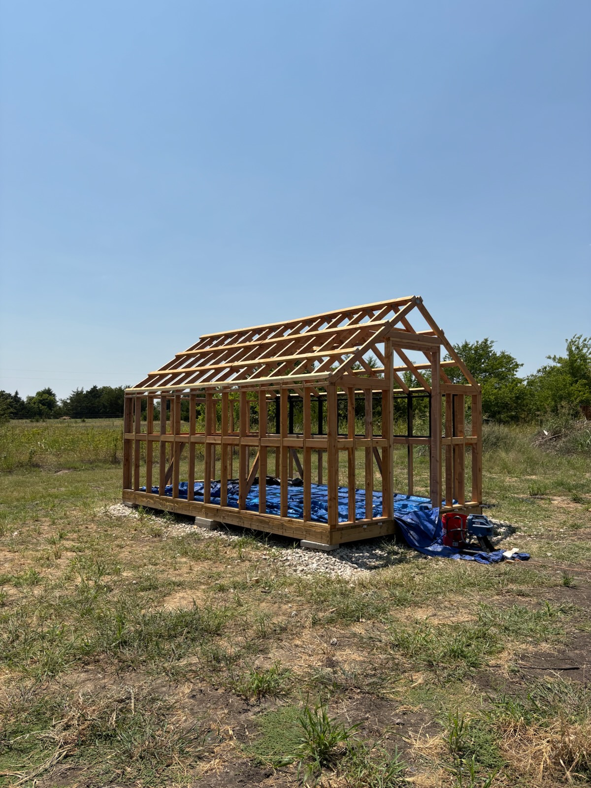 Framed shed structure with roof trusses in an open field