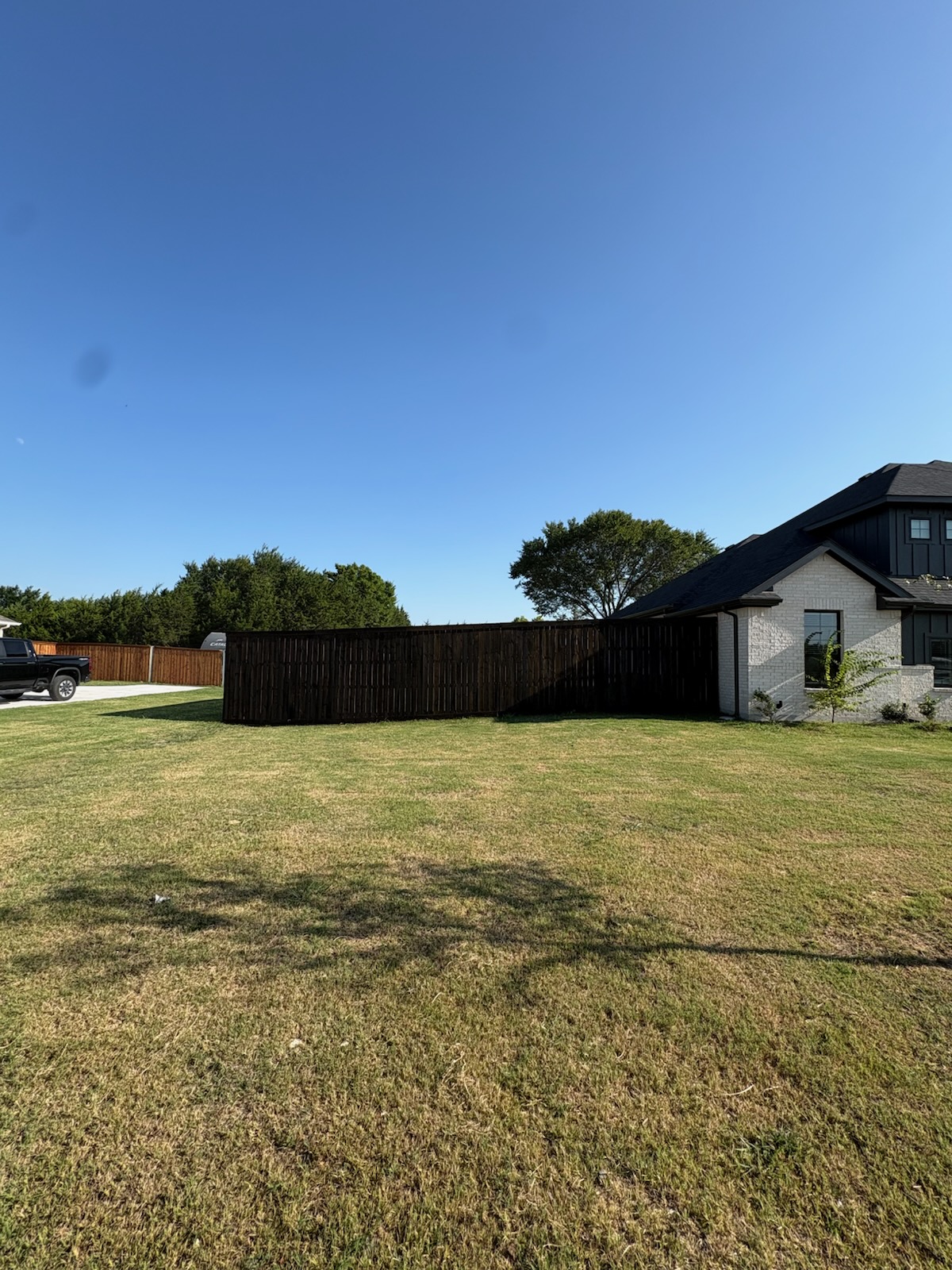 Dark stained privacy fence along a new build backyard