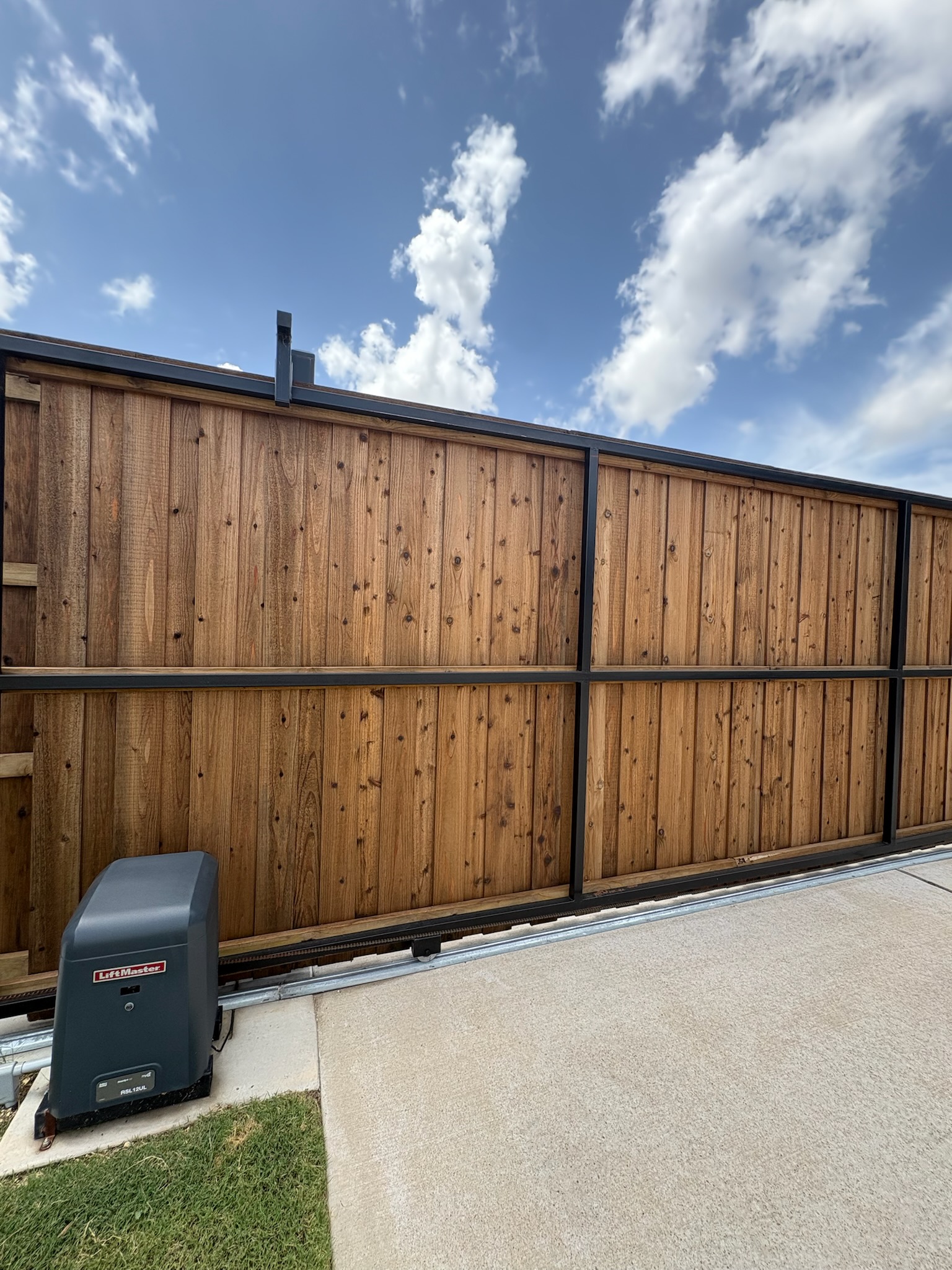 Automated sliding driveway gate with cedar panels and steel frame